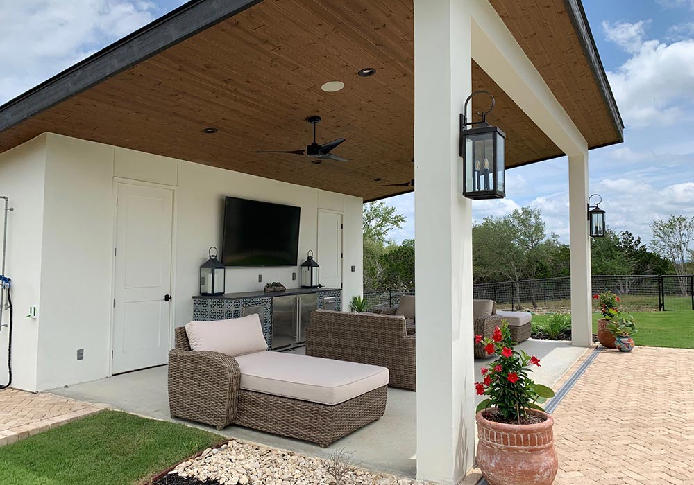 Outdoor hardscape featuring a modern patio with lounge furniture, potted plants, and wooden ceiling accents