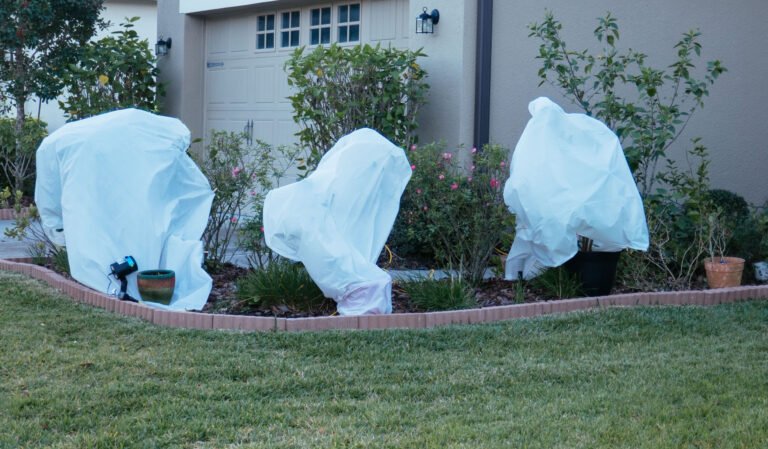 Three playful ghosts wrapped in plastic bags are hanging out in a yard, adding a spooky vibe to the scene