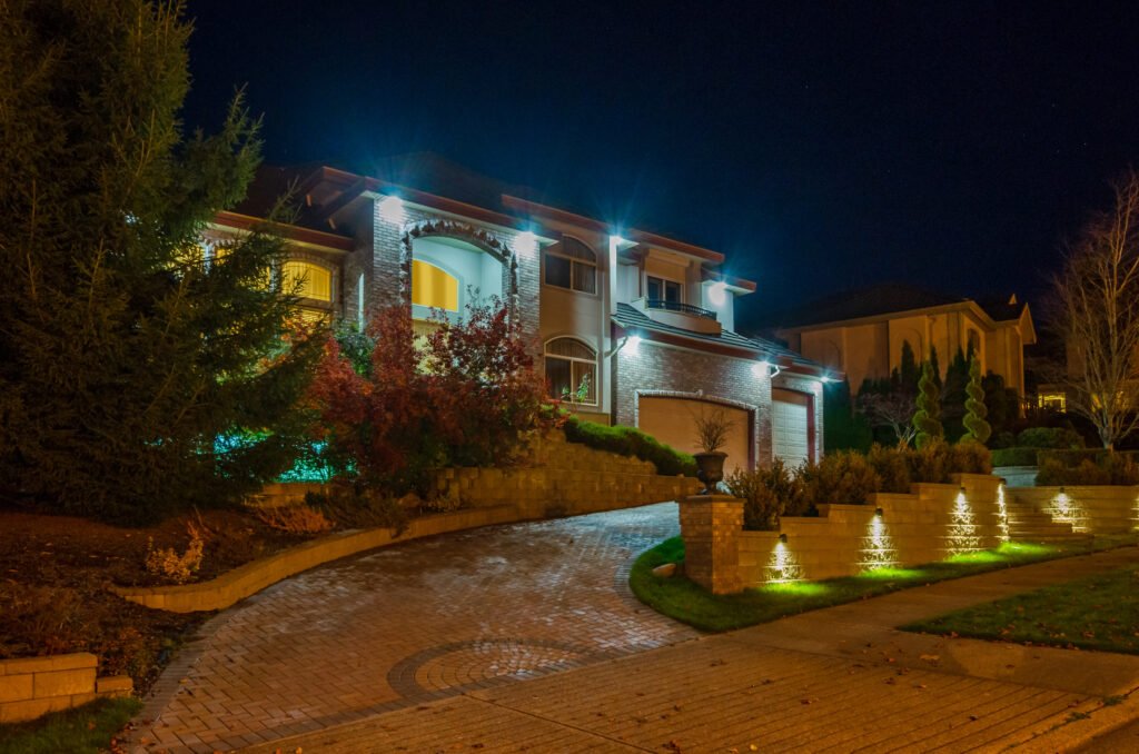 Brick driveway and stone retaining walls illuminated by strategically placed floodlights