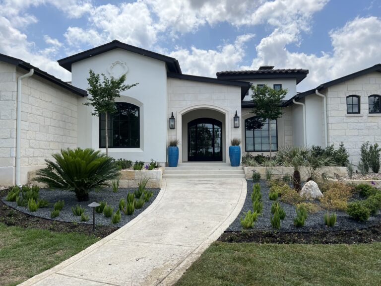 Beautiful entrance showcasing hardscapes with a curved walkway, lush landscaping, and decorative pots