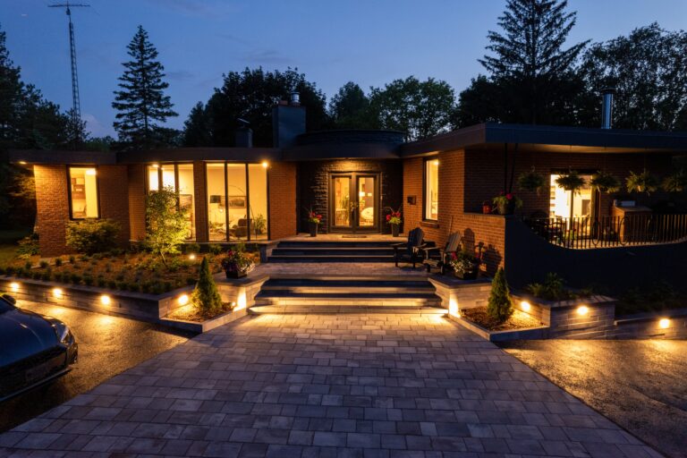 Elegant hardscapes illuminated at night, featuring a stylish entrance with stairs and landscaped lighting