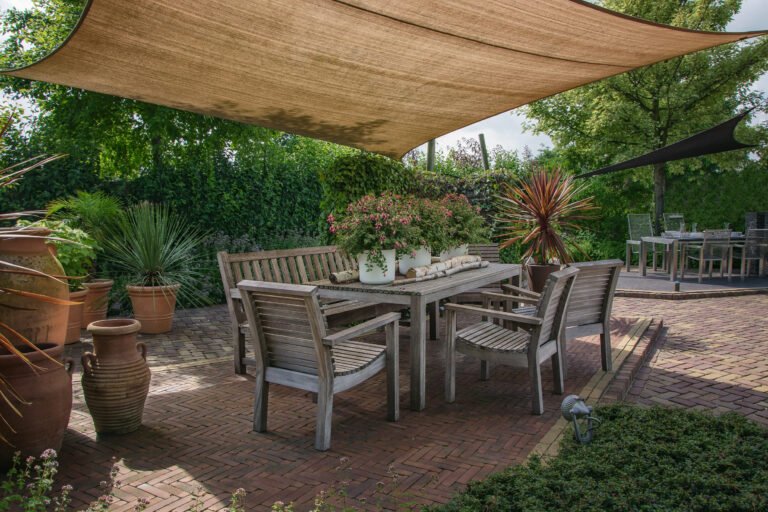 Cozy patio featuring a table and chairs under a shade, showcasing beautiful Hardscapes design