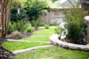 Serene backyard featuring a stone path that winds toward a vibrant flower bed, inviting tranquility