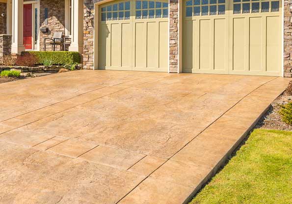 Stamped concrete driveway leading to a garage with stone accents