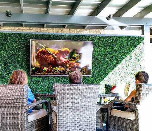 People relaxing on chairs, enjoying a TV show together on a cozy patio