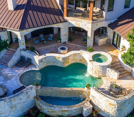 Stunning aerial view of a luxurious pool area with elegant hardscapes, including a spa and outdoor seating