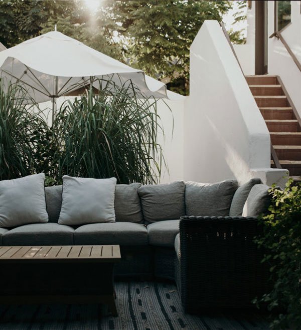 Stylish outdoor seating area with hardscapes, featuring a cozy sofa, coffee table, and an umbrella for shade