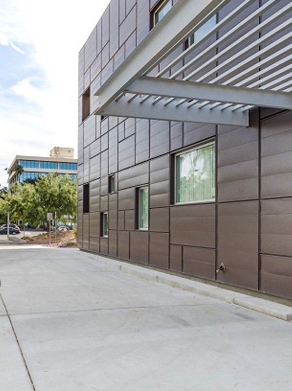 Building featuring a metal awning and a sidewalk, showcasing modern hardscapes in an urban setting