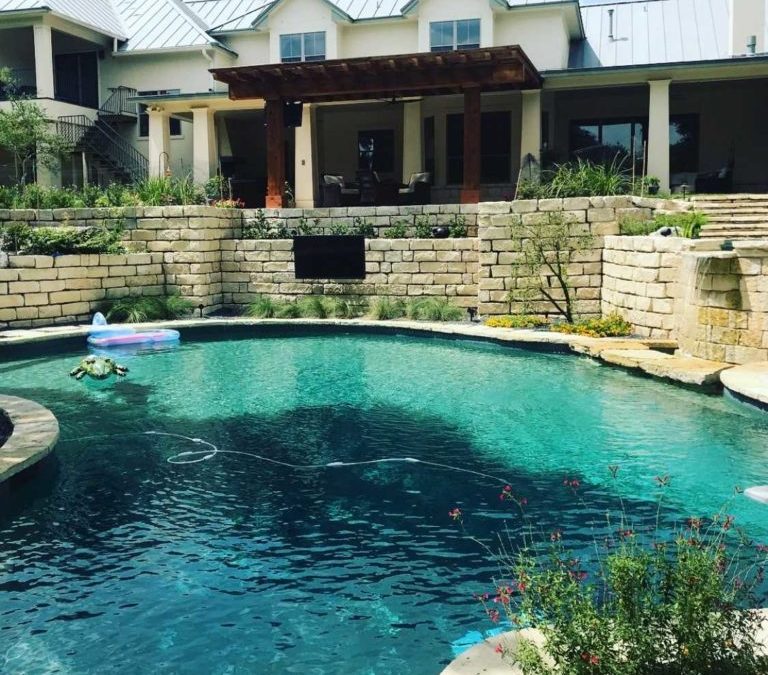 Serene backyard pool surrounded by a large stone wall, perfect for relaxation and outdoor fun