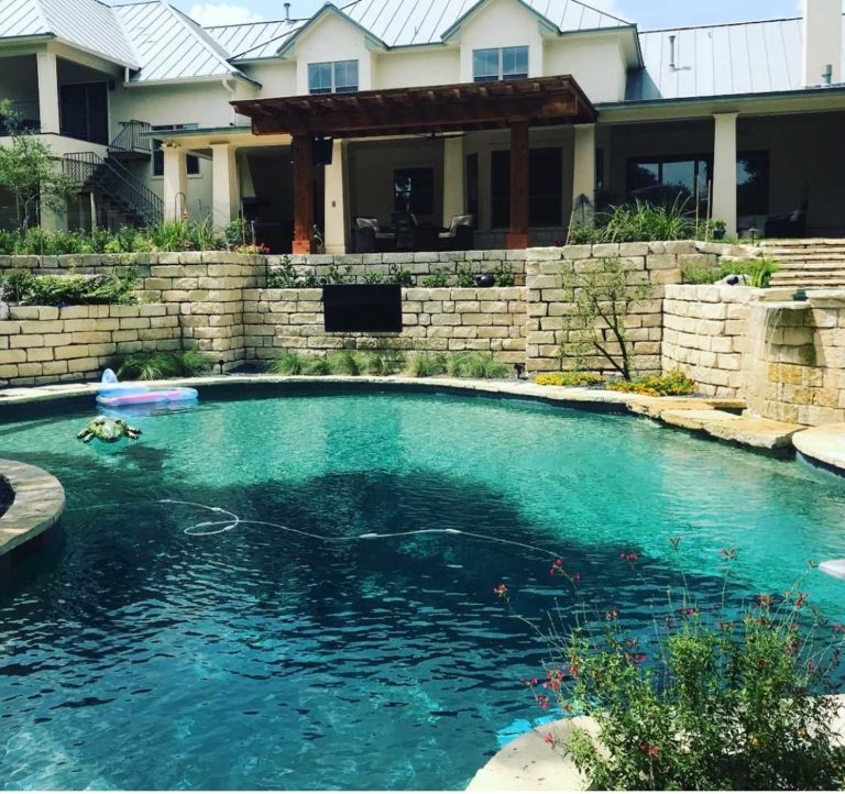 Serene backyard pool surrounded by a large stone wall, perfect for relaxation and outdoor fun