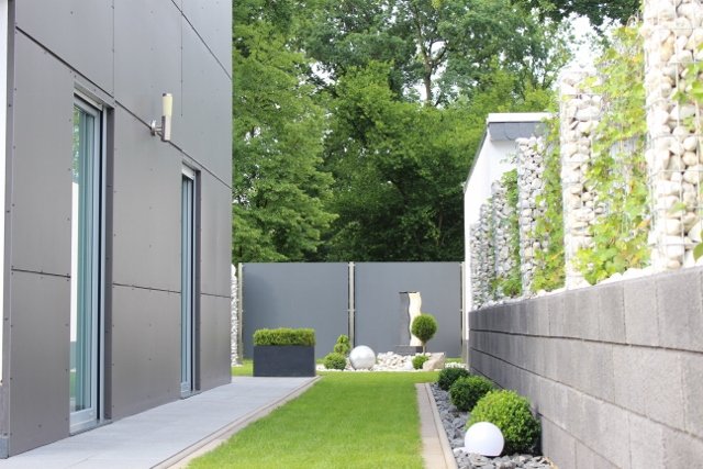 Sleek modern garden featuring a stone wall surrounded by lush green grass, creating a serene outdoor space