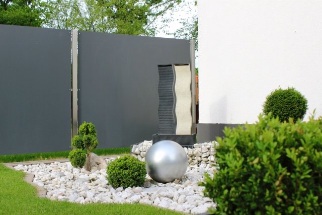 Sleek modern garden featuring a black fence and a stylish grey wall, blending nature and design