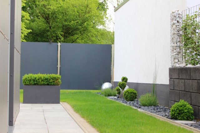 Serene garden featuring a sturdy wall and a wooden fence, surrounded by vibrant flowers and greenery