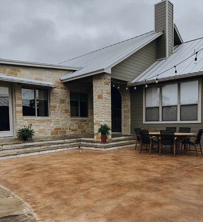 Charming home featuring a spacious stone patio, showcasing beautiful hardscapes for outdoor relaxation