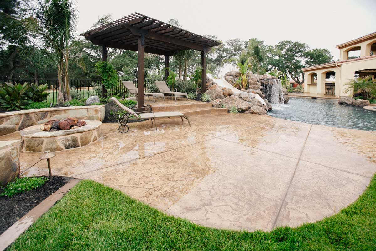 Sunny backyard featuring a pool and patio area, showcasing beautiful hardscapes for relaxation and fun