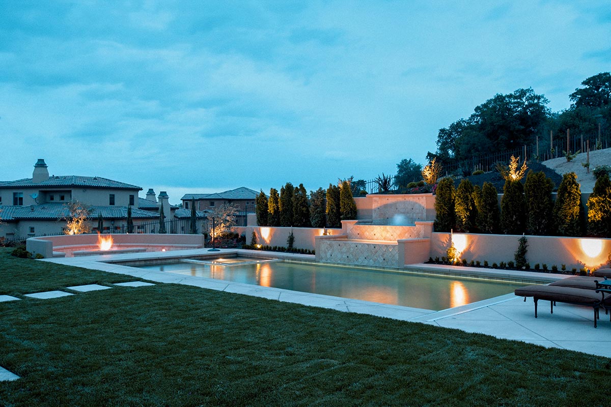 Ccozy backyard featuring a sparkling pool surrounded by soft lighting for a relaxing evening vibe