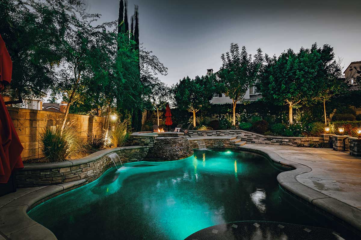 Sunny backyard featuring a pool and patio area, showcasing beautiful hardscapes for relaxation and fun