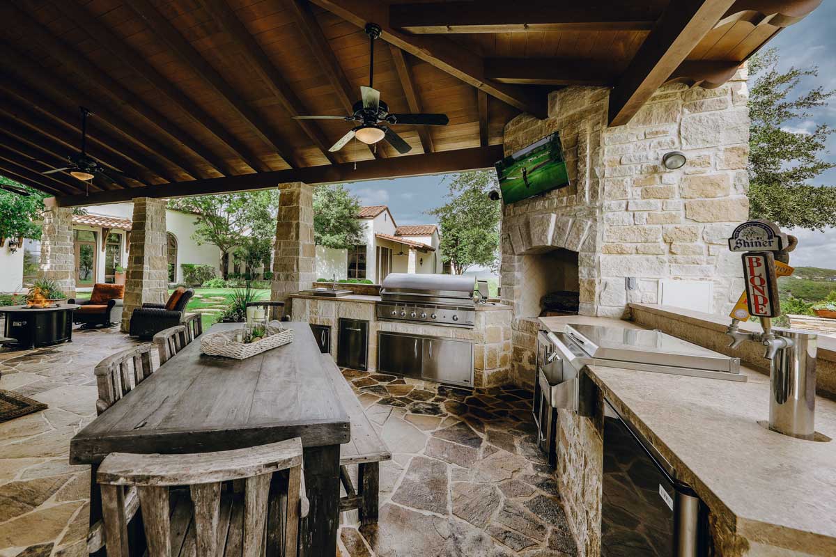 Outdoor kitchens featuring a grill and a table, perfect for cooking and dining al fresco with friends and family