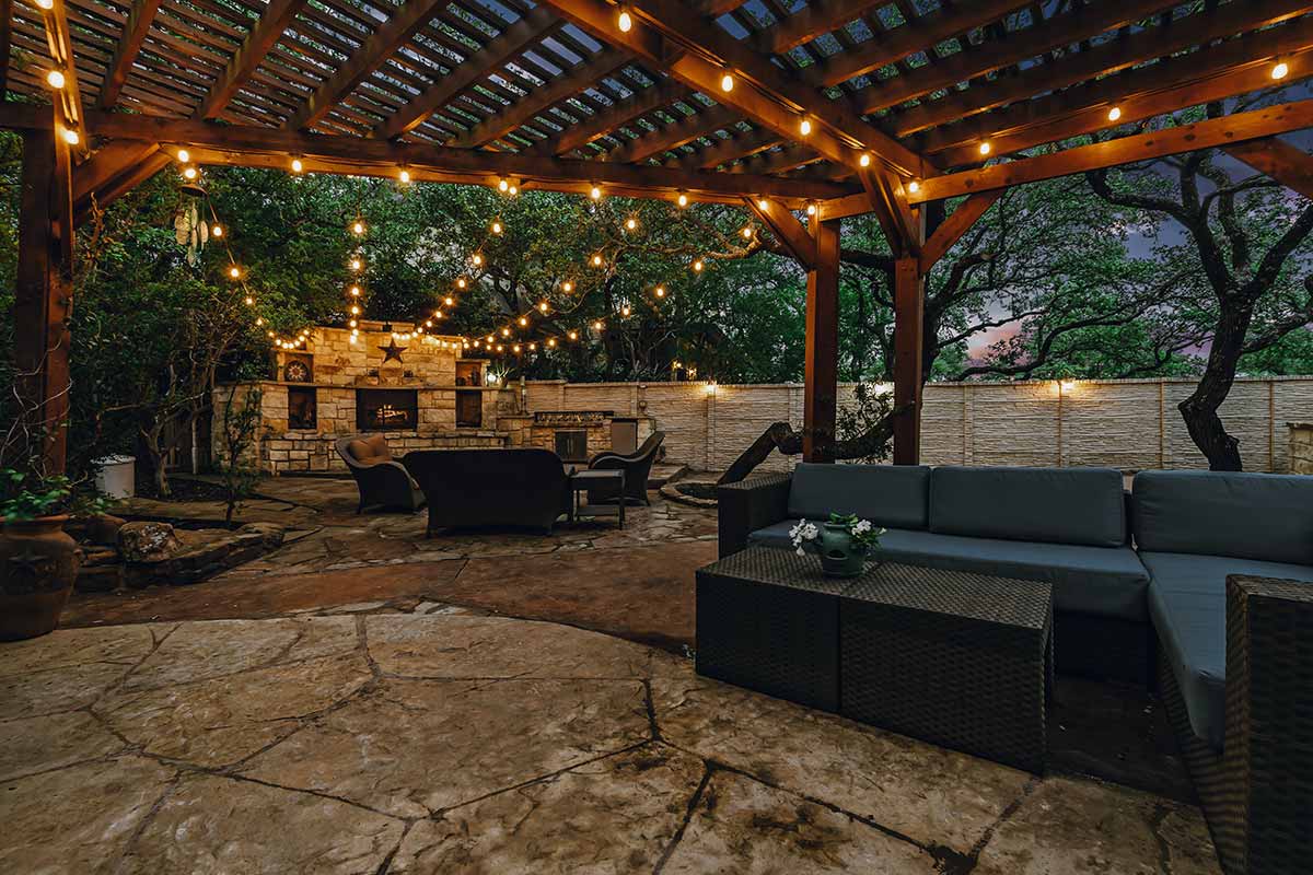 Cozy patio featuring a pergola adorned with lights, showcasing beautiful hardscapes for outdoor relaxation