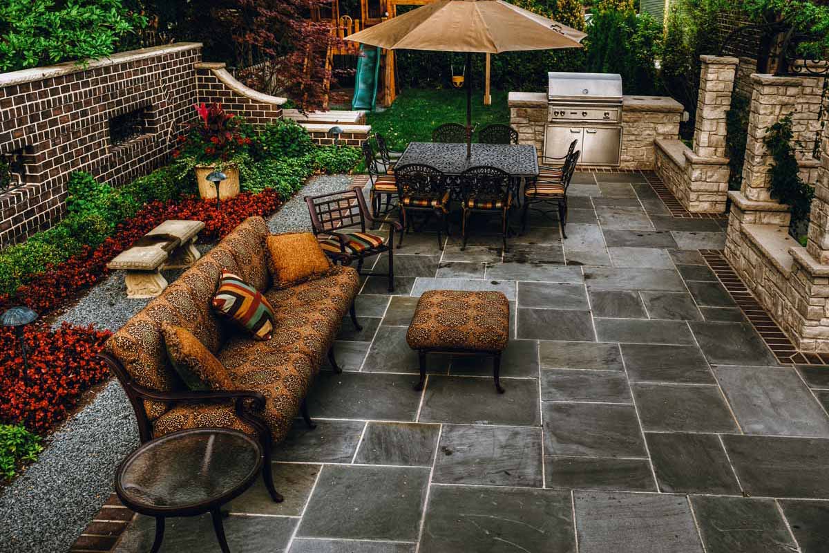 Cozy patio featuring a grill, table, and chairs, showcasing beautiful hardscapes for outdoor gatherings