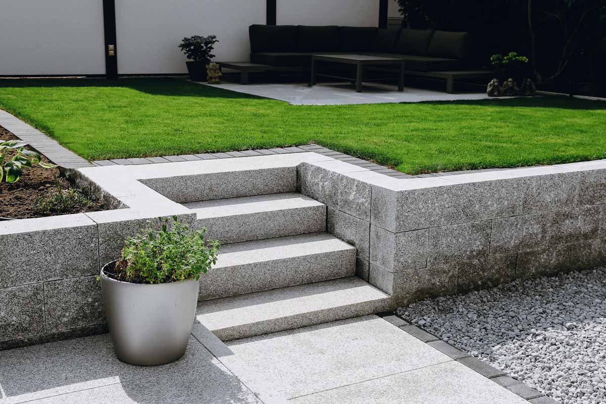 Serene garden featuring concrete steps leading to a lush lawn, showcasing beautiful hardscapes in nature