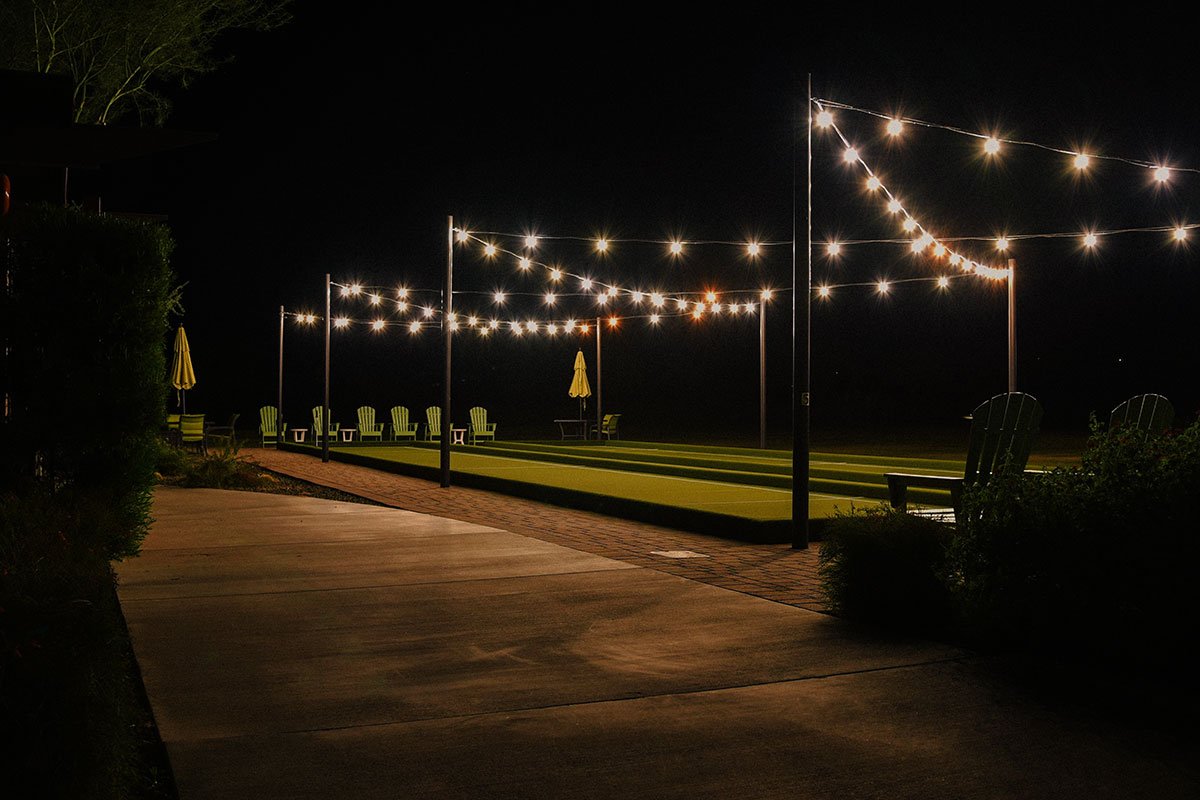 Cozy walkway adorned with string lights and lawn chairs, showcasing beautiful hardscapes for relaxation