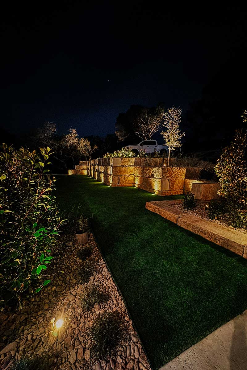 Cozy backyard featuring lush artificial turf illuminated by soft, warm lights for a relaxing atmosphere