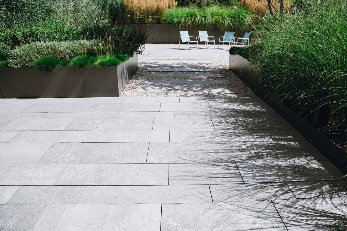 Serene walkway featuring white stone pavers surrounded by lush plants, showcasing beautiful hardscapes