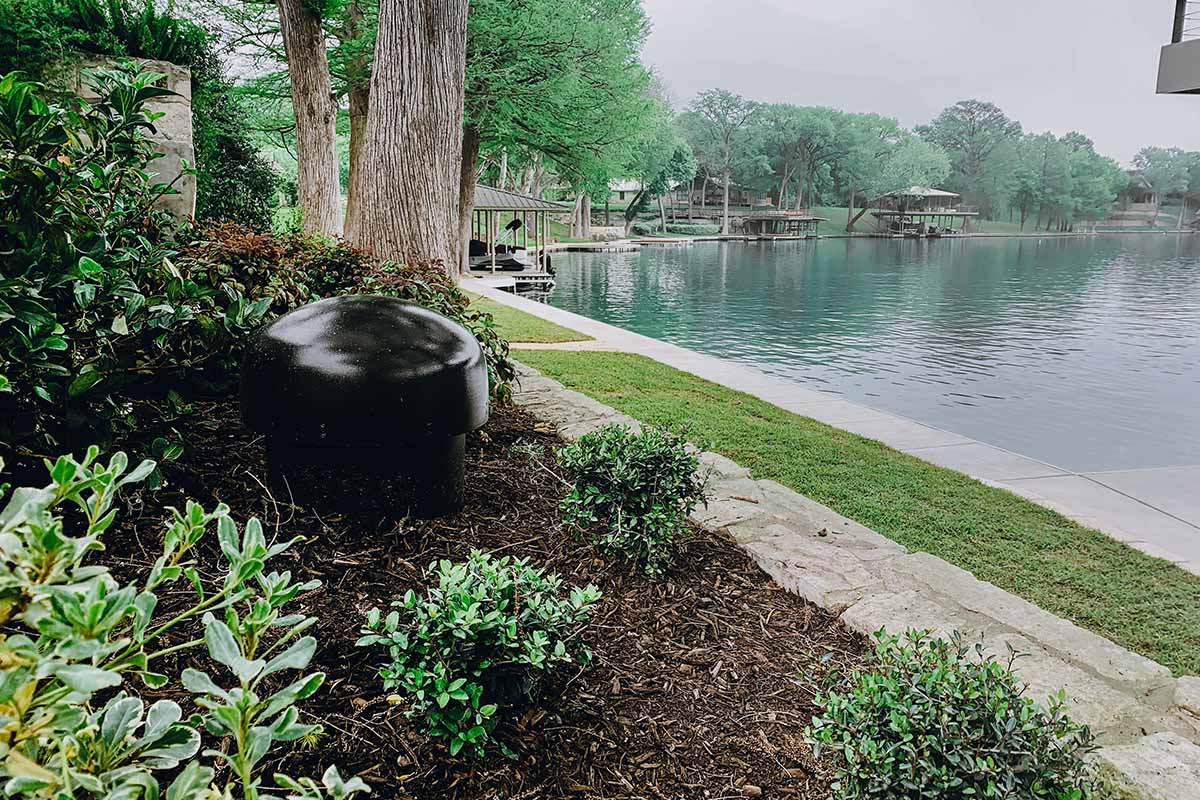 Serene lake featuring a black BBQ grill floating in the center, surrounded by calm waters and greenery