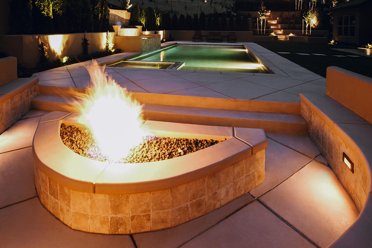 Cozy fire pit surrounded by hardscapes on a patio, glowing warmly under the night sky