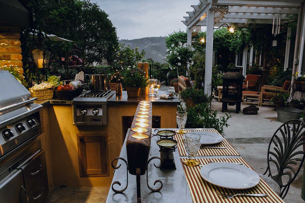 Outdoor kitchens featuring a grill and a table, perfect for cooking and dining al fresco with friends and family