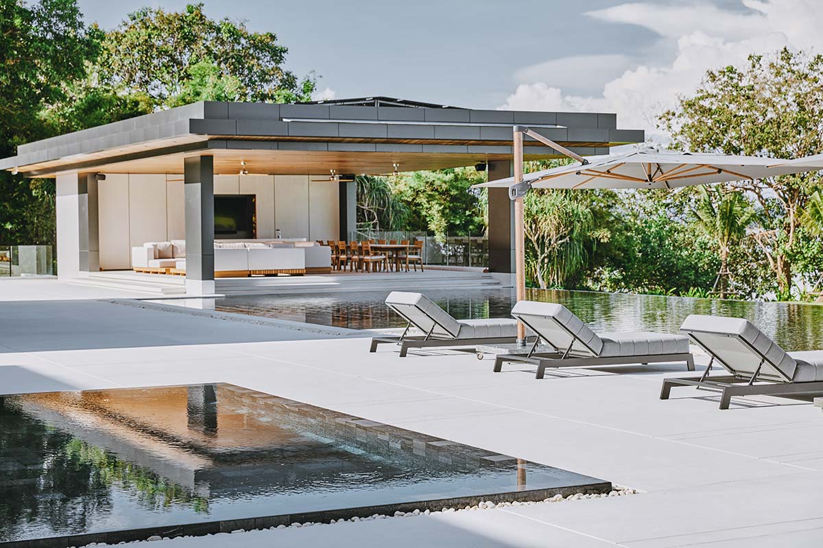 Modern pool scene featuring lounge chairs and umbrellas, showcasing beautiful Hardscapes for relaxation