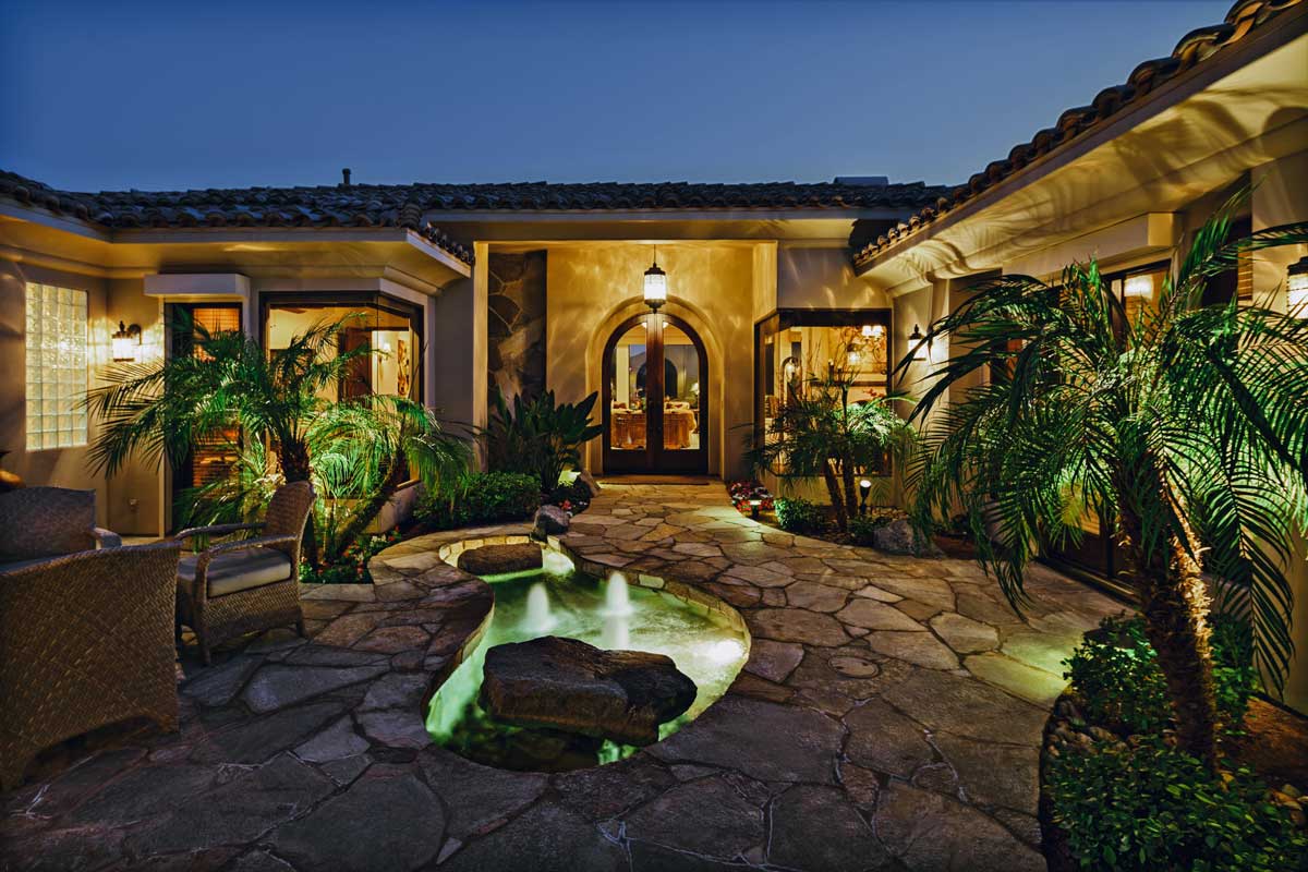 Stunning home featuring a fountain and palm trees, showcasing beautiful hardscapes in the landscape