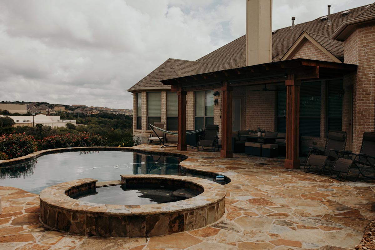 Serene pool surrounded by a pergola and patio, showcasing beautiful hardscapes for relaxation