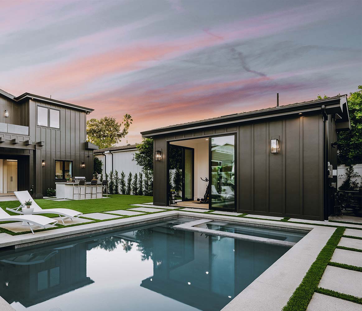 Modern home featuring a pool and lounge chairs, showcasing beautiful hardscapes for outdoor relaxation