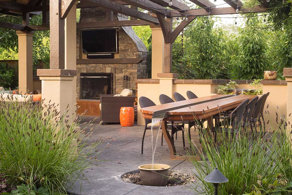 Cozy patio featuring a table and chairs, a fireplace, and beautiful water features for relaxation