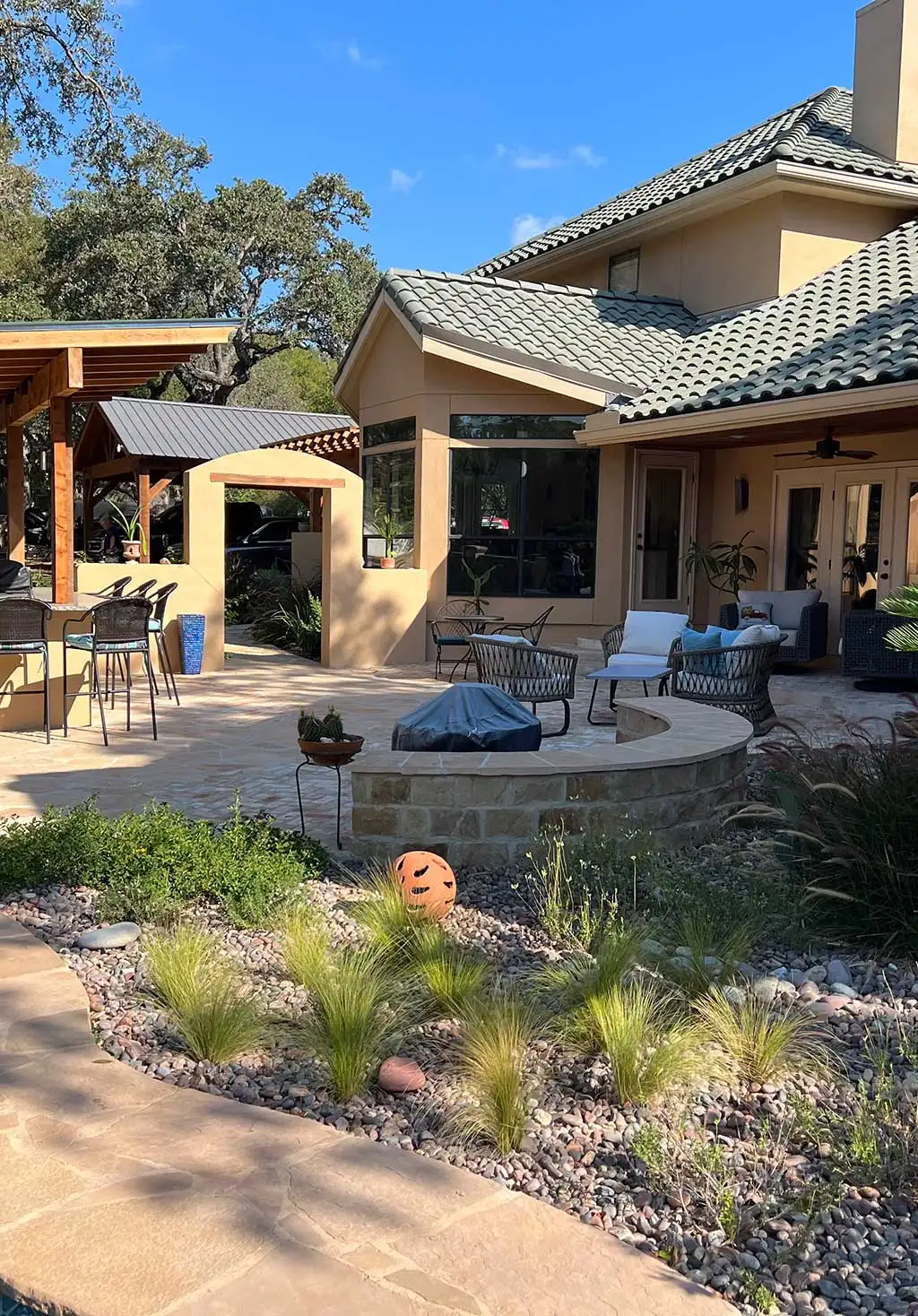 Backyard patio with lounge chairs, fire pit, and vibrant Softscapes, featuring ornamental grasses and a stone path