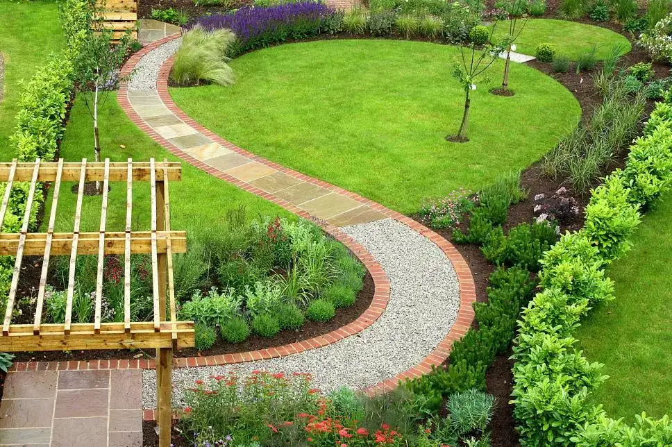 Curved pathway bordered by lush greenery and vibrant plants, showcasing Softscapes in a well-maintained garden