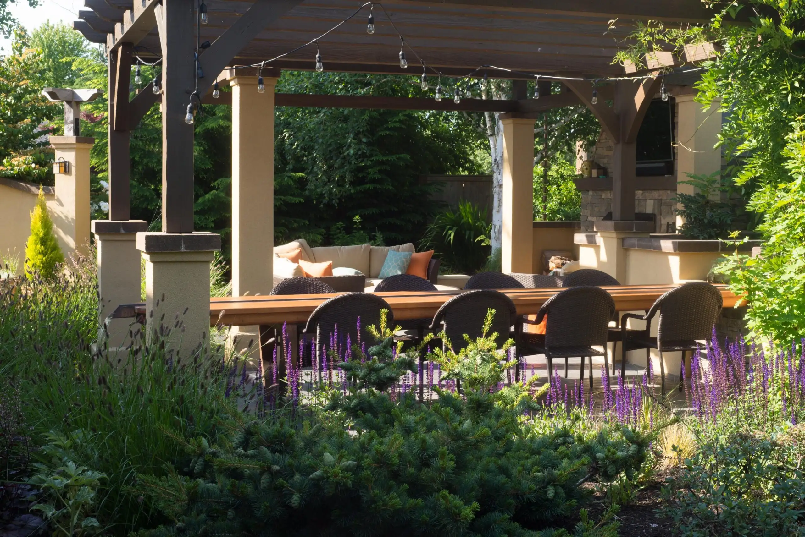 Cozy backyard pavilion with dining area, surrounded by lush greenery and vibrant plants, highlighting Softscapes