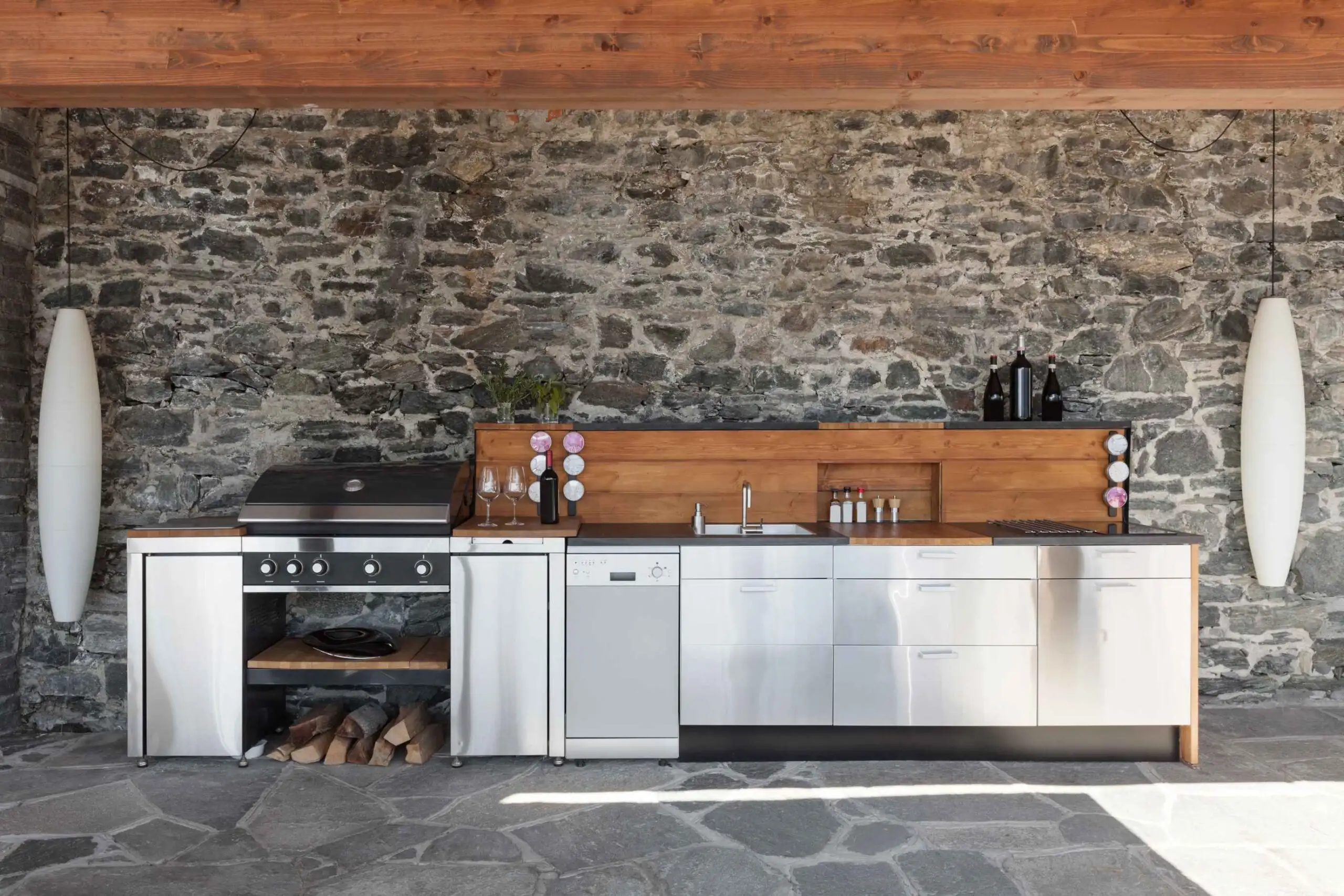 Modern outdoor kitchens with stainless steel appliances, stone walls, and a wooden countertop for a rustic feel