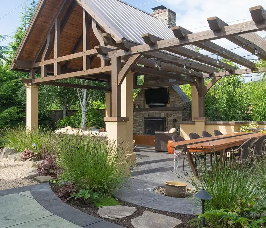 Backyard with a wooden pergola structure, outdoor dining area, stone fireplace, and integrated hardscapes pathways