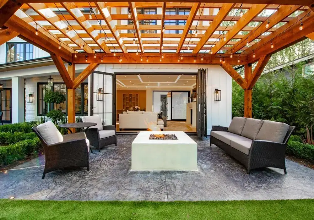 Stylish outdoor kitchens with a wooden pergola, modern seating, a fire pit, and an open transition to indoor living space