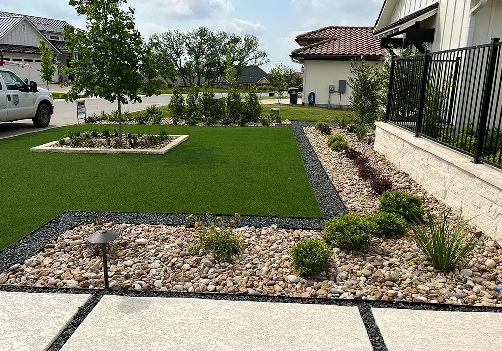 Modern residential lanscape featuring a neatly manicured lawn, gravel borders, and young trees with minimalistic design