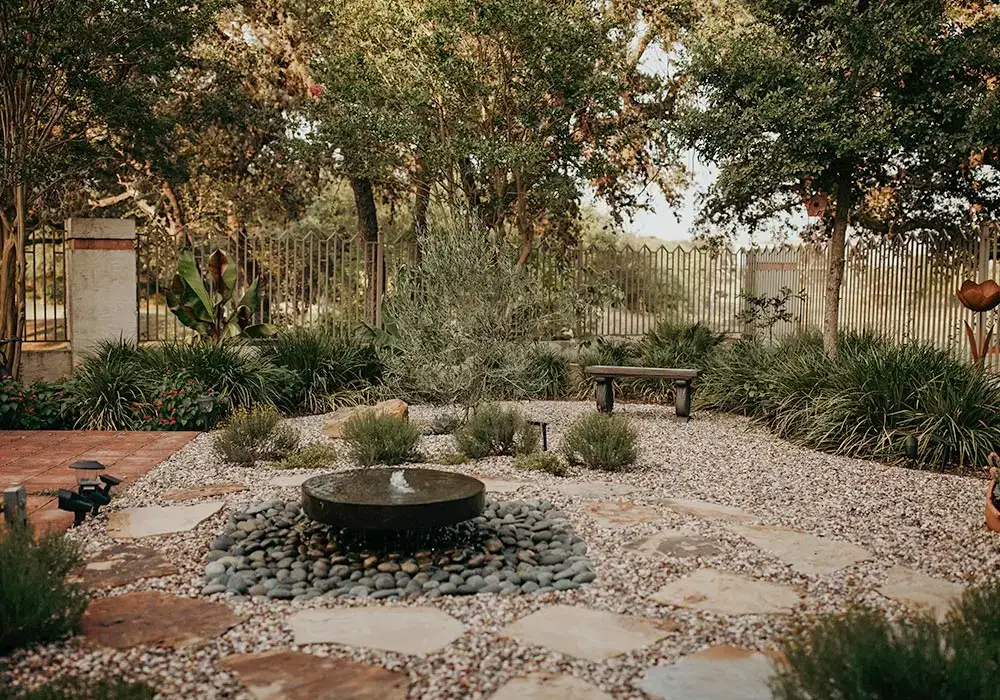 Peaceful courtyard with stone hardscapes, a central water feature, and surrounding greenery for a tranquil atmosphere