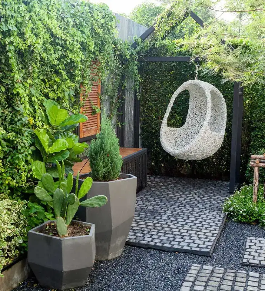 Cozy garden with a modern swing, paver hardscapes, and lush greenery, featuring sleek potted plants