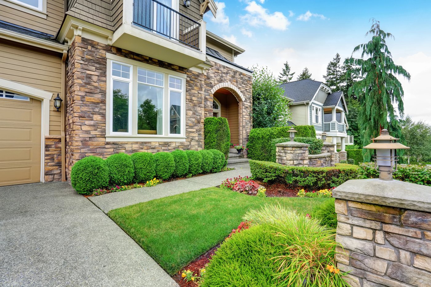 Trimmed shrubs and lawn along the frontage of a stone and stucco home in Monte Vista, TX