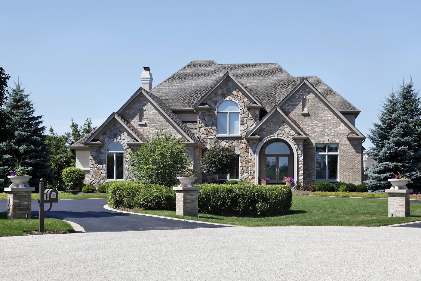Landscaped front lawn and driveway at a brick and stone home in Olmos Park, TX